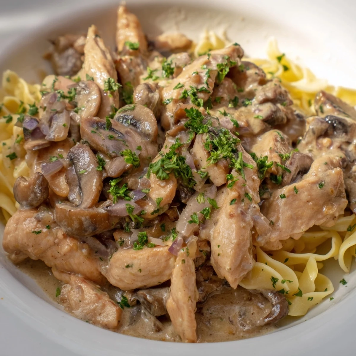 Creamy chicken stroganoff bubbling in a skillet, the rich sauce coating tender chicken and mushrooms.