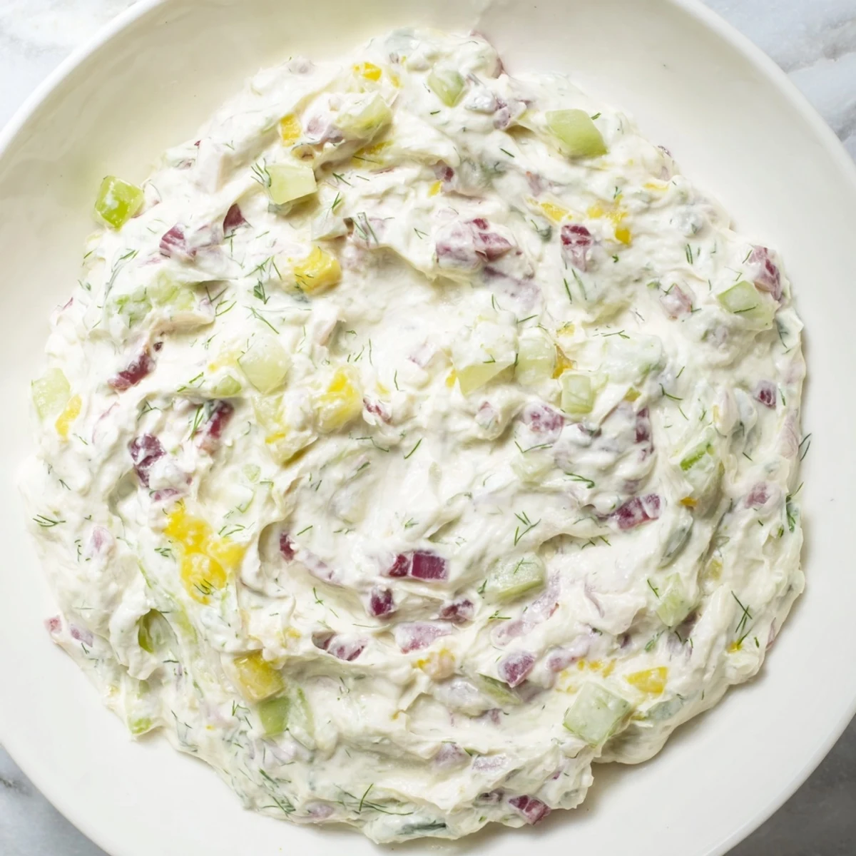 Creamy sweet and sour pickle relish dip with visible bits, perfect for dipping chips at a party.