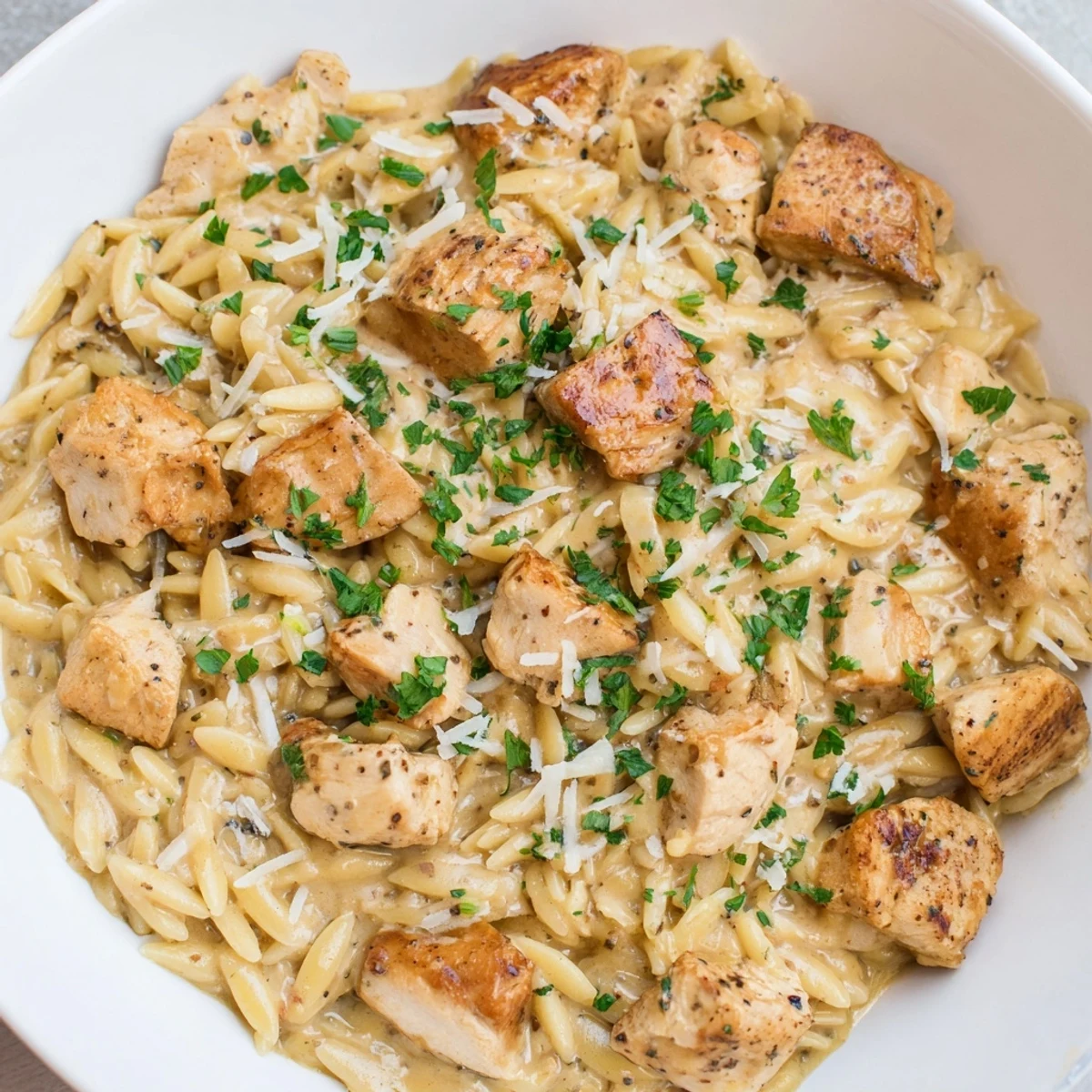 A steaming bowl of One-Pot Cajun Chicken Alfredo Orzo, rich with Parmesan and parsley garnish.