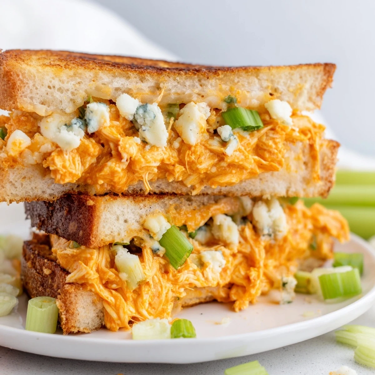 Mouthwatering close-up of a Buffalo Chicken Grilled Cheese, with a creamy filling and crispy edges.