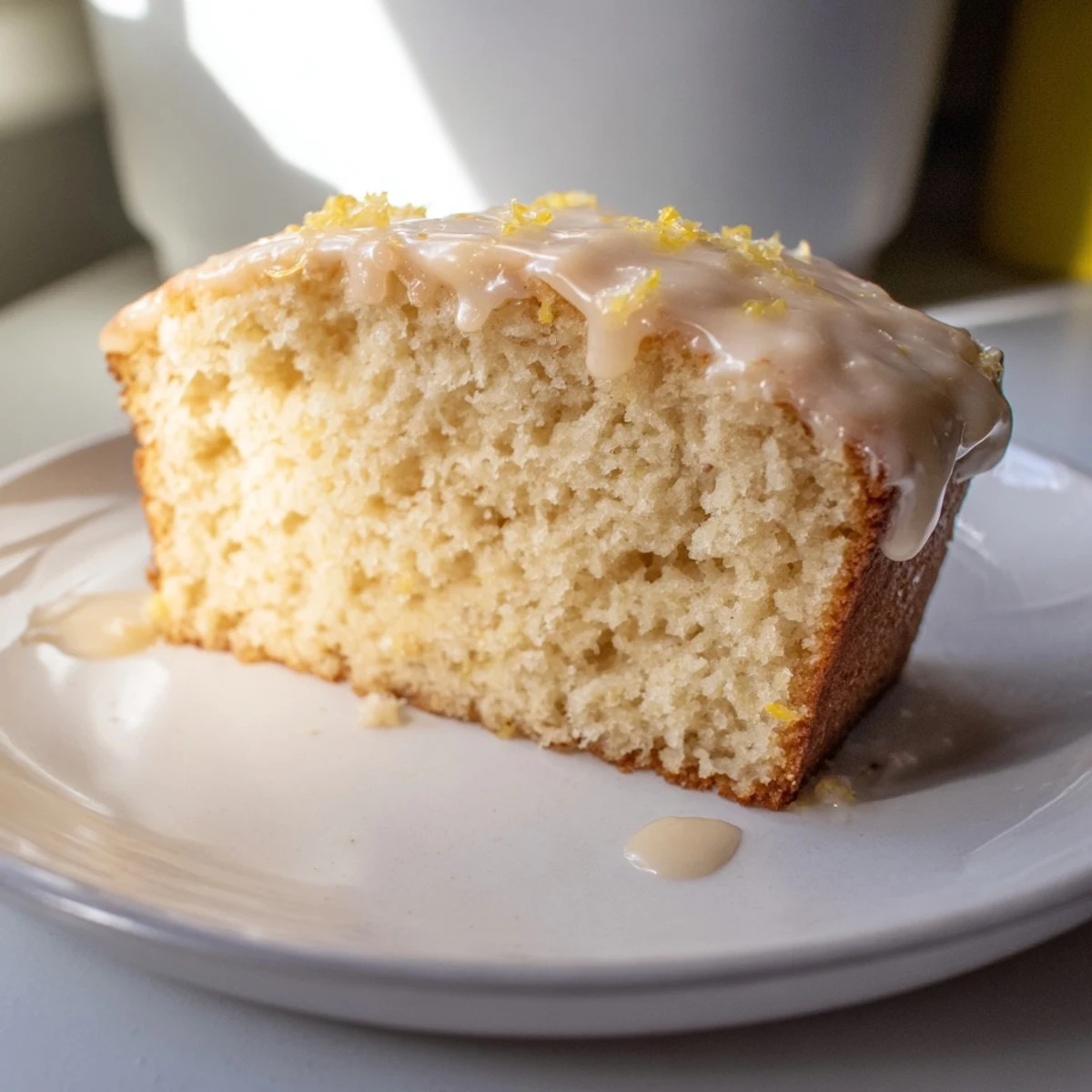 Golden slice of Lemon Yogurt Cake, drizzled with sweet glaze, ready for a delightful bite.
