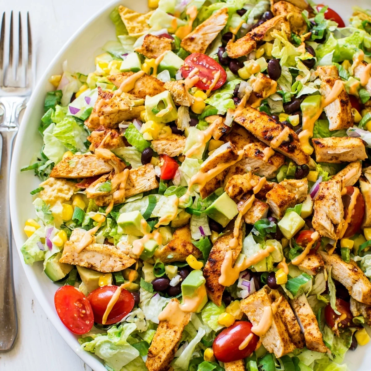 A close-up of Crunchy Taco Chicken Salad with seasoned chicken, black beans, and golden crushed taco shells over crisp romaine.