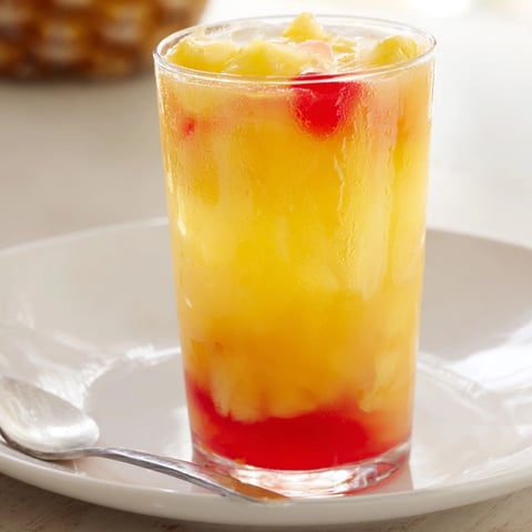 Refreshing Tropical Pineapple Punch: golden juice swirling in a glass with frothy fizz.
