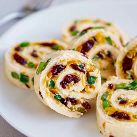 Vibrant cranberry jalapeño cream cheese pinwheels arranged on a festive platter.  