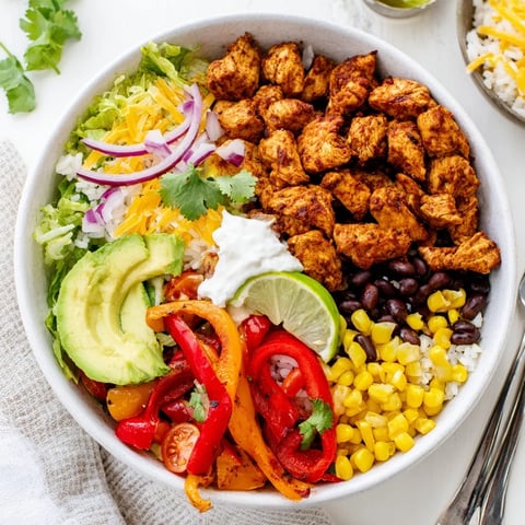 Juicy Sheet Pan Chicken Burrito Bowls topped with fresh avocado and cilantro.  