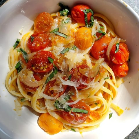 Steaming, one-pan Cozy Fireplace Tomato Basil Pasta, garnished with fresh basil and Parmesan cheese.