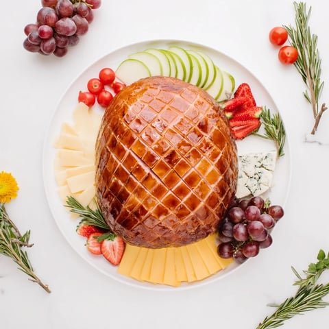 A holiday-ready Glazed Ham Centerpiece Board with glistening ham alongside colorful cheeses and fruits.