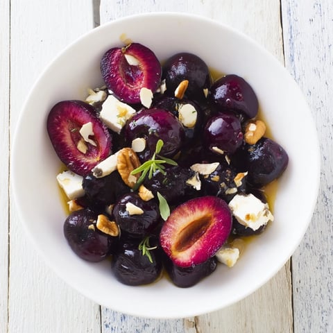 The Midnight Orchard features dark cherries, plums, grapes, and creamy goat cheese arranged artfully on a platter.