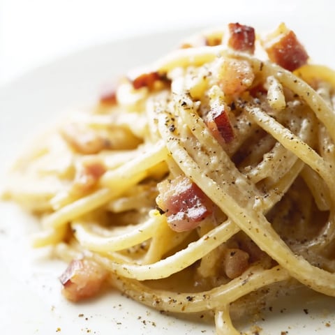 A close-up shot of creamy Express Spaghetti Carbonara garnished with fresh Parmesan cheese.
