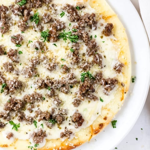 Ground Beef Alfredo Pizza boasts melted mozzarella atop a richly sauced, savory ground beef base.