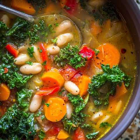 In a rustic white bowl, Mediterranean White Bean Stew features tender white beans, vibrant carrots, and kale in a rich, tomato-based broth garnished with fresh parsley.