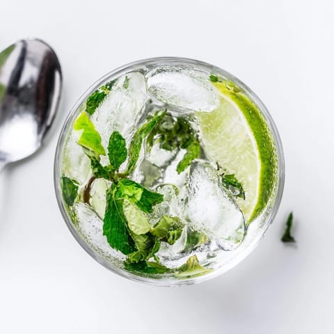 Icy cold mojito: a vibrant blend of lime, mint, rum; garnish with lime wedge.
