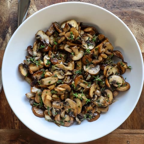 A vibrant close-up of Enchanted Forest Mushrooms, perfectly sautéed, with a delicate wine sauce, perfect for a side.