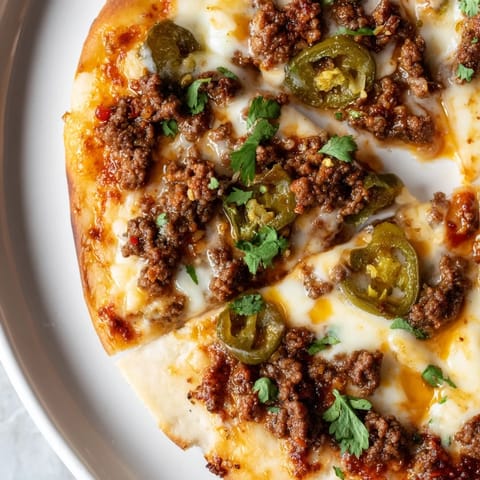 Golden-crusted spicy ground beef pizza, topped with melted mozzarella and a drizzle of hot honey.