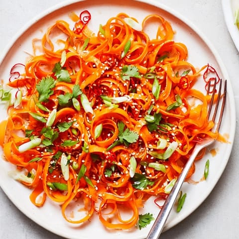 Colorful Asian-style carrot ribbon salad served as a refreshing vegan side or light appetizer.  