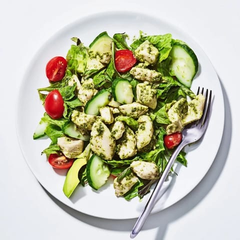Gluten-free Green Goddess Chicken Salad on a bed of mixed greens, cherry tomatoes, and crunchy cucumber slices.