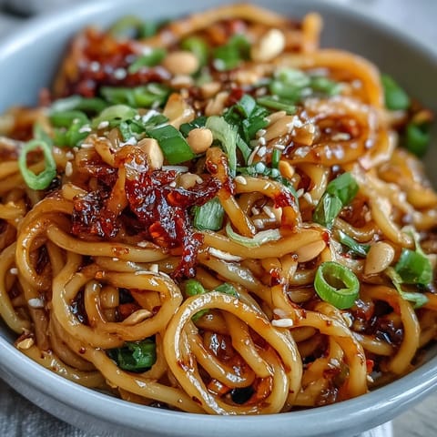 Vibrant bowl of chili crisp noodles tossed with crunchy chili oil, soy sauce, and aromatic garlic for bold flavor.  