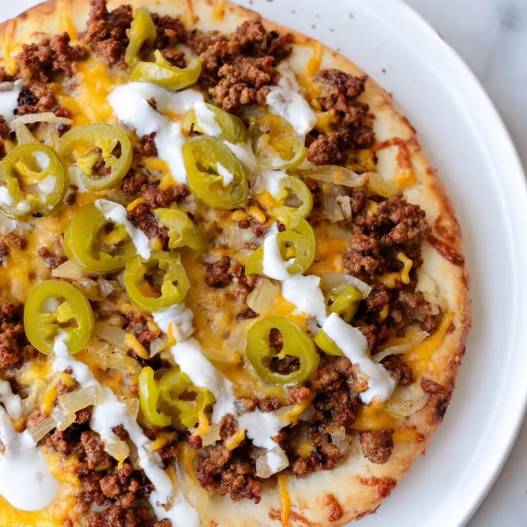 Enjoy a slice of homemade Ground Beef Taco Pizza with a creamy sour cream drizzle, a family favorite.