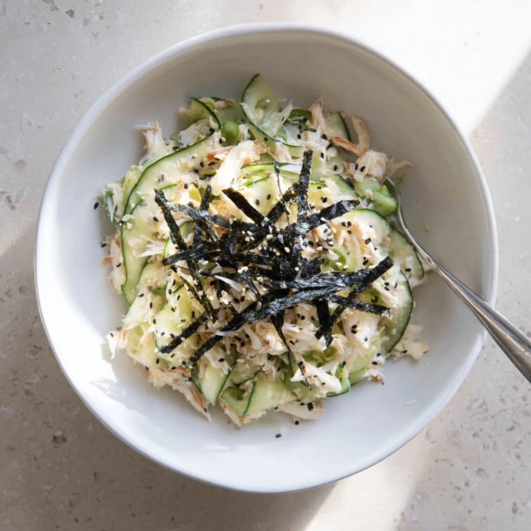 California Roll Cucumber Salad served chilled in a white bowl, garnished with pickled ginger and scallions for a bright, Japanese-American appetizer.
